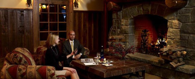 Businessman and woman sitting by a fireplace.