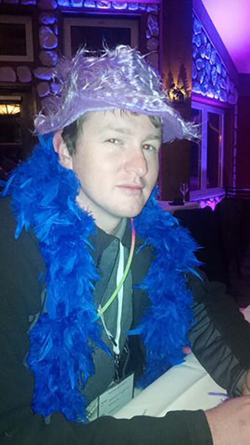 Employee wearing feather boa and hat. The Whiteface Lodge