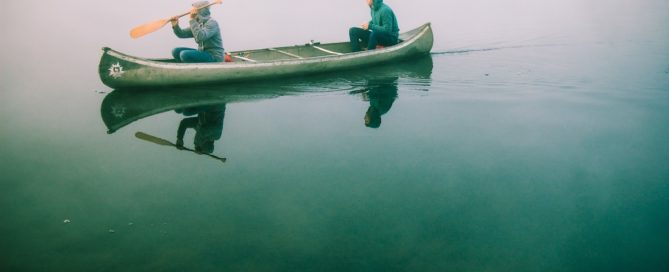 Couple in a canoe on a foggy lake.