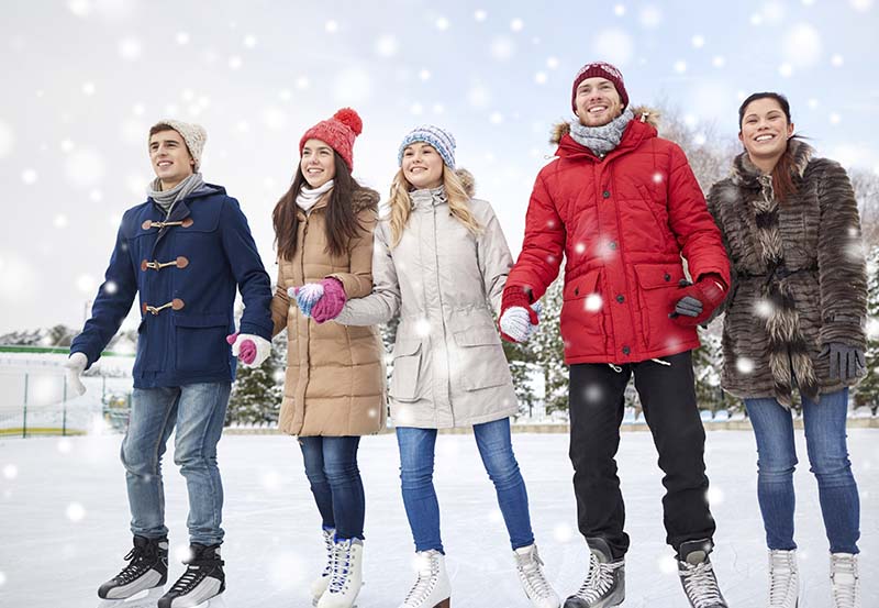 happy friends ice skating on rink outdoors The Whiteface Lodge