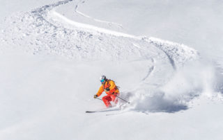 A skier heading down a mountain in Lake Placid with ski rentals