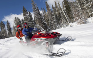 A couple riding on a Lake Placid snowmobile rentals