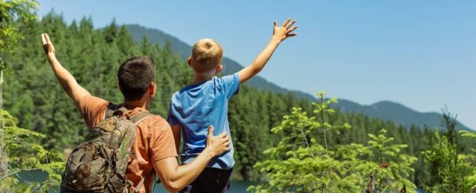 A father and son hiking in Lake Placid, enjoying a view of the mountains and trees