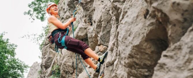 A smiling woman rock climbing in the Adirondacks