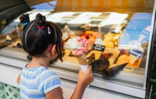 A young girl holding an ice cream cone at an ice cream parlor in Lake Placid