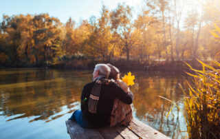 A couple admiring fall foliage on a lakeside dock in Lake Placid