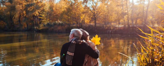 A couple admiring fall foliage on a lakeside dock in Lake Placid