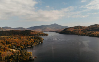 A fall day in Lake Placid, with orange and brown trees covering mountains and a view of the lake