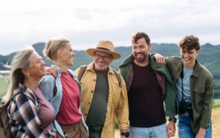 A multigenerational family smiling on a hike during a vacation to Lake Placid, NY