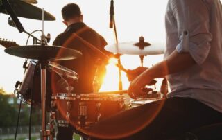 A drummer and guitarist playing at sunset at Songs at Mirror Lake concert series