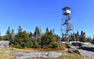 A fire tower perched at the summit of a mountain in the Adirondacks